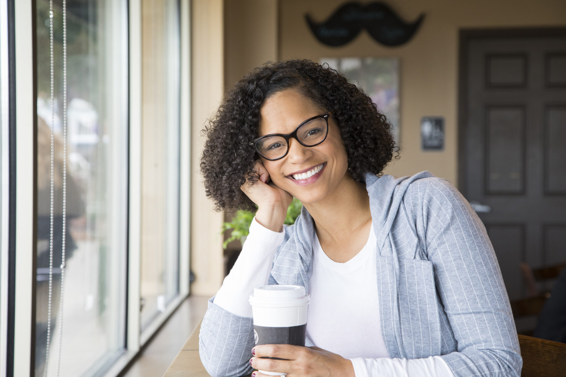A woman wearing glasses holding a cup of coffee